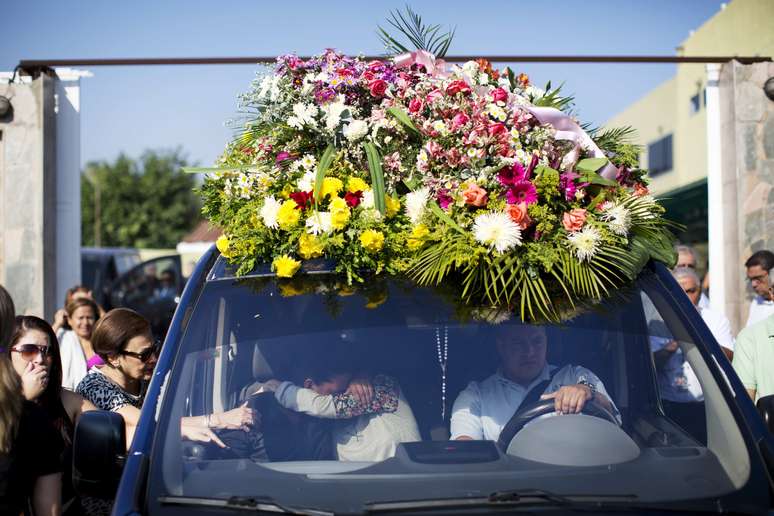 Familiares de Génesis Carmona se abraçam dentro do carro fúnebre que leva o corpo da modelo, durante seu funeral na sexta-feira, 21 de fevereiro