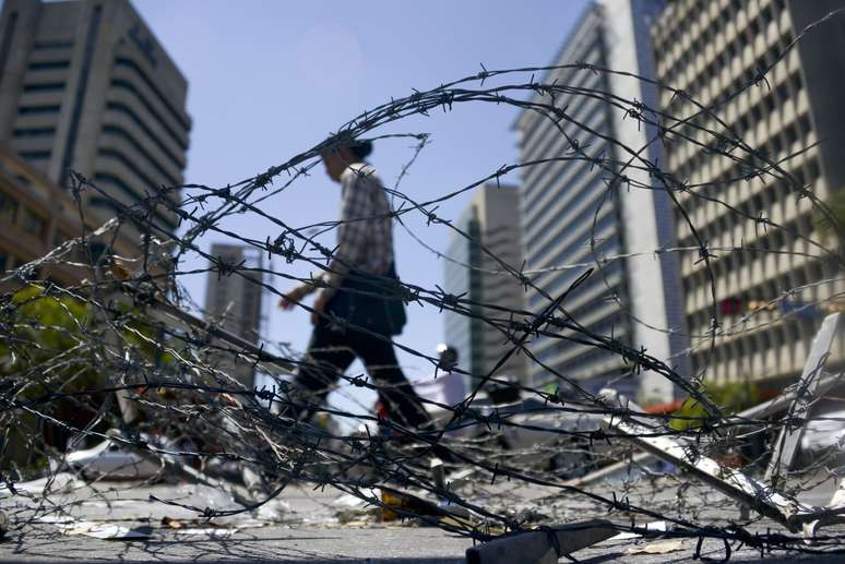 <p>Homem passa por barricada colocada por manifestantes anti-governistas em Caracas, em 21 de fevereiro</p>