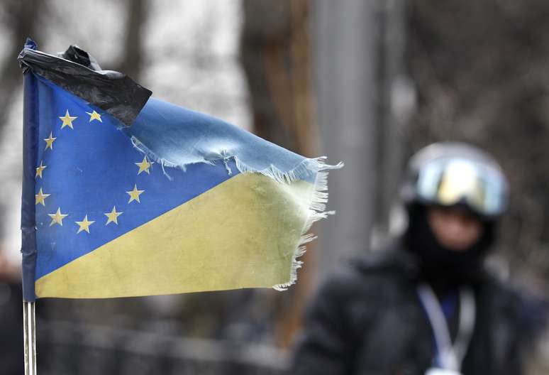 <p>Em gesto simbólico, uma fita preta foi colocada em uma bandeira que combina as bandeiras da Ucrânia e da União Europeia. A simbologia marca um dia de luto nas ruas de Kiev</p>