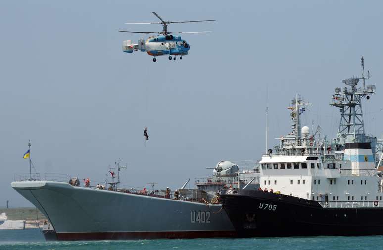 Helicóptero russo sobrevoa navio de guerra ucraniano durante exercício militar em Sebastopol, em maio de 2011