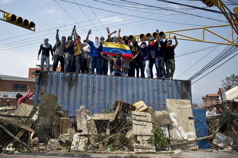 <p>Manifestantes sobem em um cont&ecirc;iner, usado como barricada em uma rua de San Crist&oacute;bal, capital do estado de Tachira, na Venezuela</p>