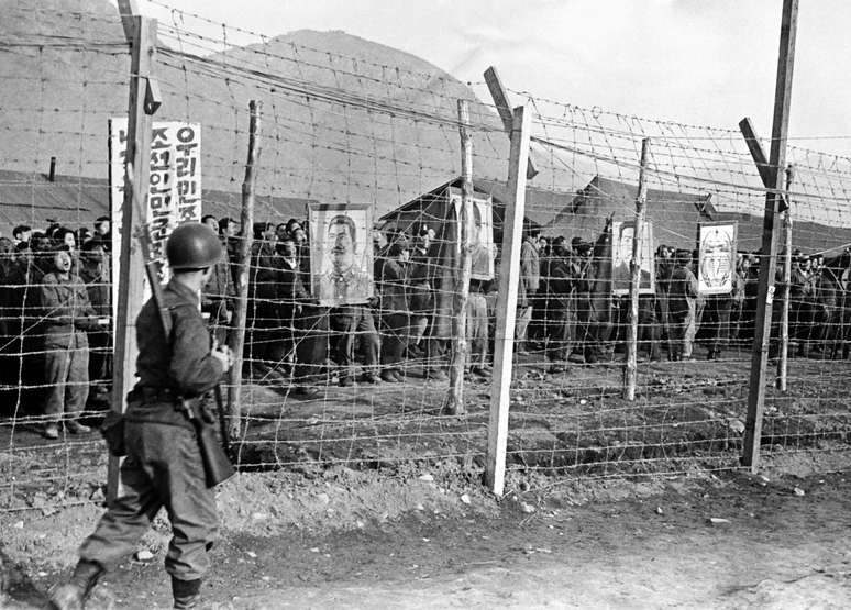 Foto de 1952 dos campos que mostra prisioneiros norte coreanos e chineses segurando retratos dos líderes comunistas, Stalin e Mao Tse-Tung