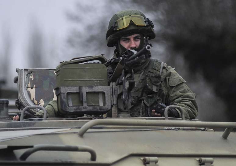 Homem uniformizado olha de cima de um veículo militar enquanto tropas tomam o controle dos escritórios da Guarda Costeira em Balaclava, periferia de Sevastopol, Ucrânia, neste sábado
