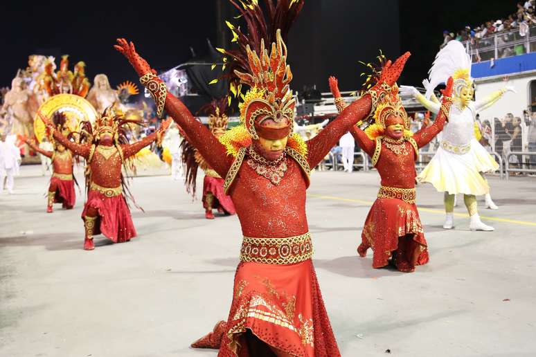 Passistas com fantasias que representa a fé ajoelham durante desfile da escola de samba Mocidade Alegre em São Paulo