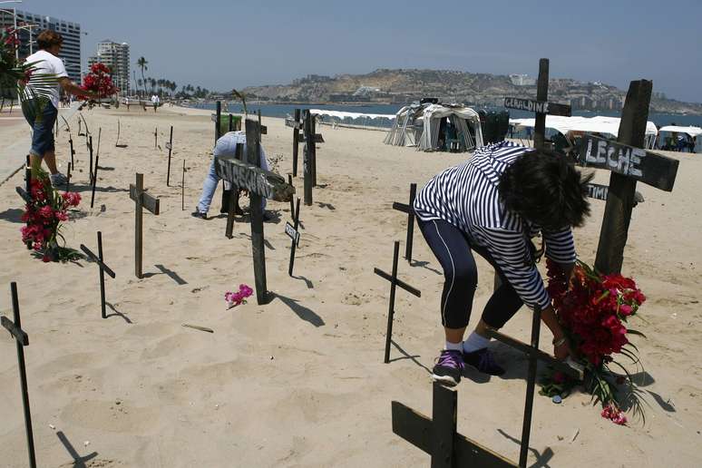 <p>Cruzes com nomes de v&iacute;timas da viol&ecirc;ncia na Venezuela s&atilde;o fixadas nas areias da praia em Puerto La Cruz</p>