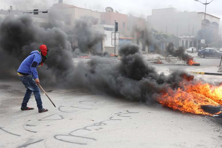 Manifestante líbio coloca fogo em pneus, bloqueando rua na capital do país, próximo ao Congresso