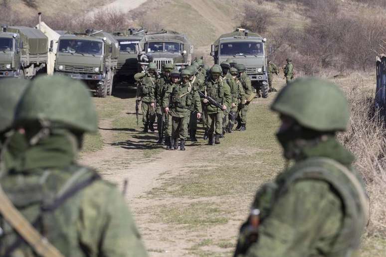 Tropas tidas como forças militares russas andam pelo lado de fora de uma base militare ucraniana, na vila de Perevalnoye, próxima a Simferopol. A Ucrânia afirmou que a Rússia está mobilizando veículos blindados de seu lado da fronteira próximo da região ucraniana da Crimeia desde que o presidente Vladimir Putin disse ter o direito de invadir seu vizinho, desencadeando um venda generalizada de ações russas. 03/03/2014