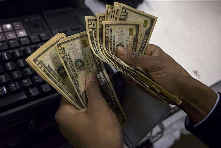 Un cajero cuenta dólares al interior de una tienda de la cadena Macy's en Nueva York, nov 28 2013. El dólar y el yen se apreciaban el lunes debido a que los inversores buscaban activos de refugio, en momentos en que la intervención militar de Rusia en la península ucraniana de Crimea avivaba las tensiones geopolíticas.