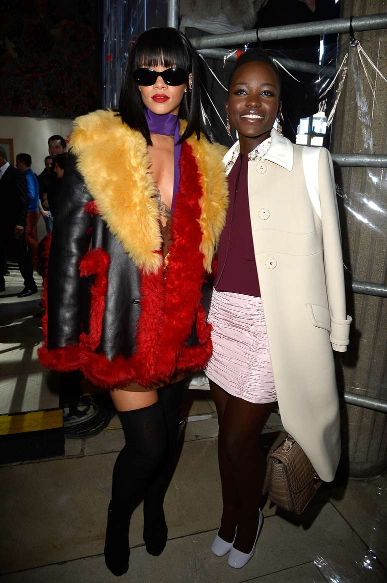 <p>Rihanna e Lupita Nyong&#39;o , vencedora do Oscar de Melhot Atriz Coadjuvante, estiveram no desfile da grife Miu Miu, segunda marca da Prada. Rihanna usou um dos casacos desfilados pela Prada, em Mil&atilde;o, com pele colorida. A pe&ccedil;a &eacute; legal, mas ficaria melhor com uma cal&ccedil;a do que com a bota cuissarde. Rihanna, por&eacute;m, pode. Lupita optou por algo mais simples e sem erro: saia, su&eacute;ter e casaco. Um sapato escuro teria ficado melhor no look e ajudaria a alongar</p>