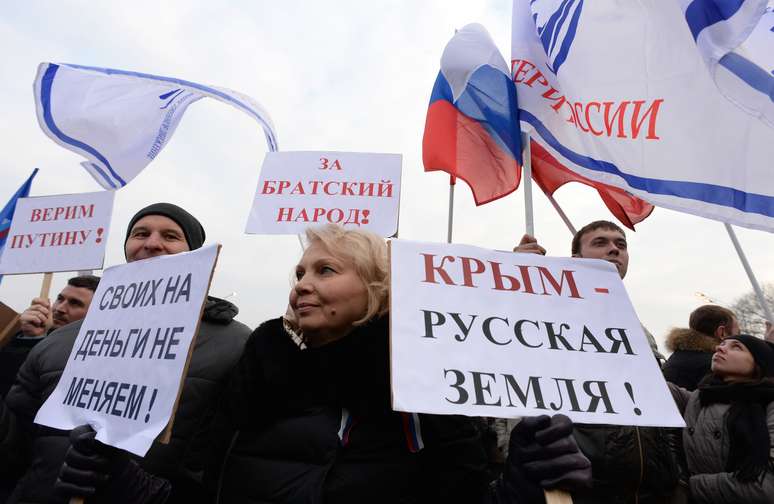 Mulher segura uma placa com a frase "Crimeia é terra russa!" e "Não mudamos nossas pessoas por dinheiro!" durante protesto no centro de Moscou, nesta sexta-feira, 7 de março