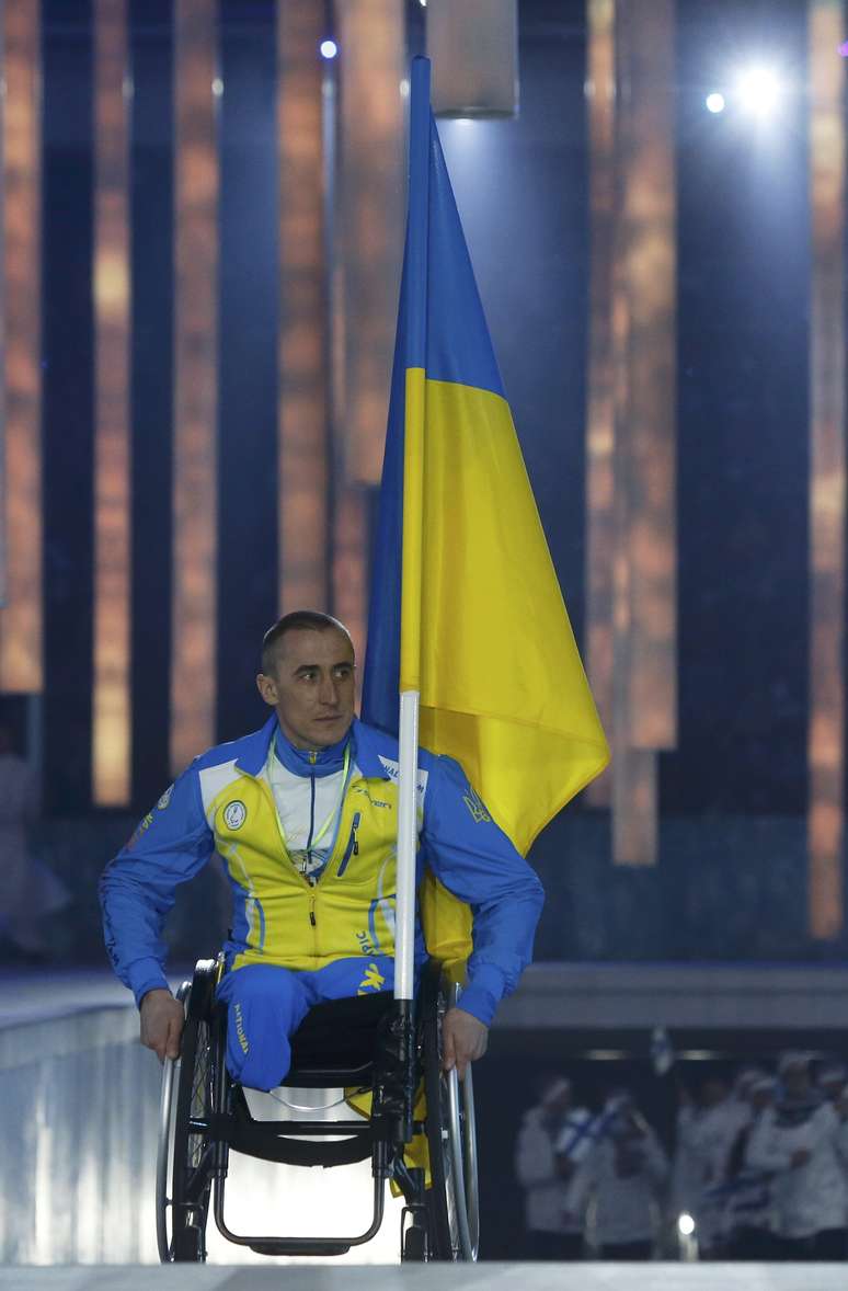 Mykhaylo Tkachenko carrega a bandeira da Ucrânia na cerimônia de abertura
