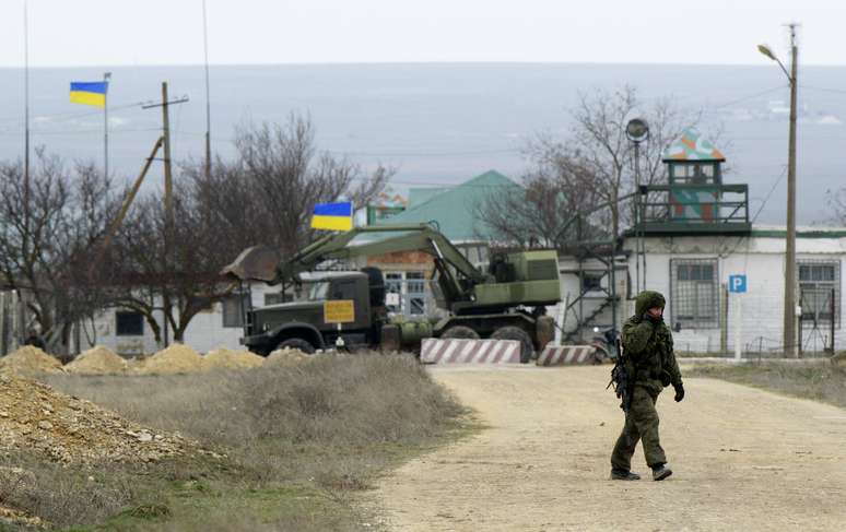 Homem armado, provável soldado russo, caminha próximo a base naval ucraniana no porto da Crimeia de Yevpatorva, neste sábado, 8 de março