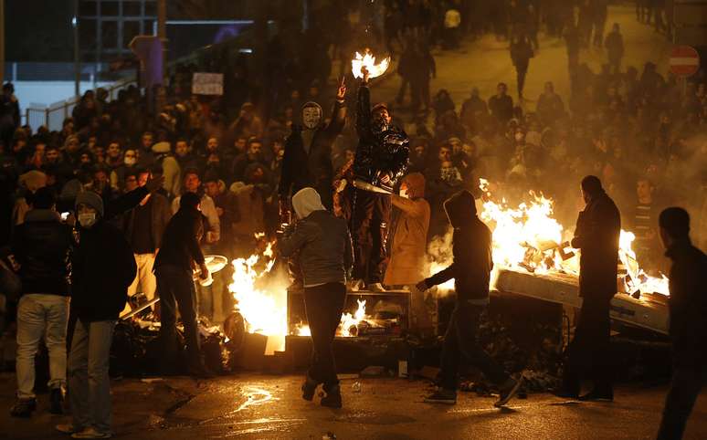 <p>Manifestantes contra o governo se protegem das forças policias atrás e barricadas durante protesto em Ankara, na noite de 12 de março</p>