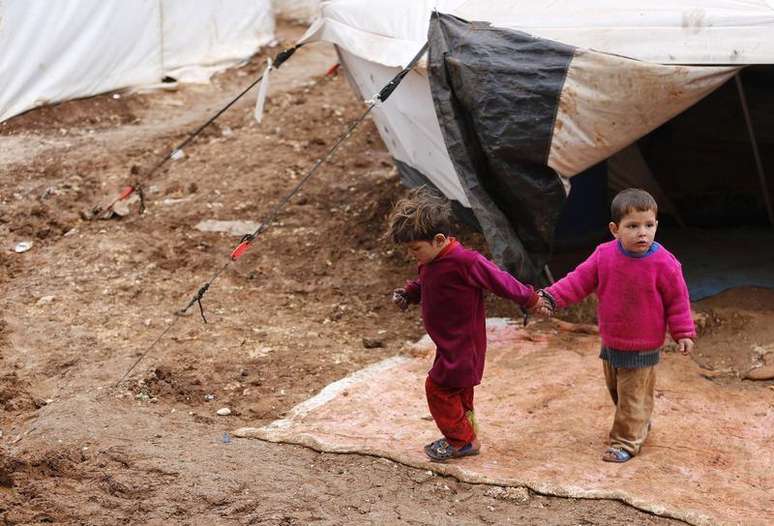 Crianças sírias refugiadas andam pela lama no campo de refugiados Bab Al-Salam, em Azaz. O governo da Síria prometeu maior acesso para os grupos de ajuda que prestam assistência a milhões de sírios, mas é preciso progredir mais rápido para lidar com a grave crise humanitária, disse o chefe do Unicef nesta sexta-feira. 14/03/2014