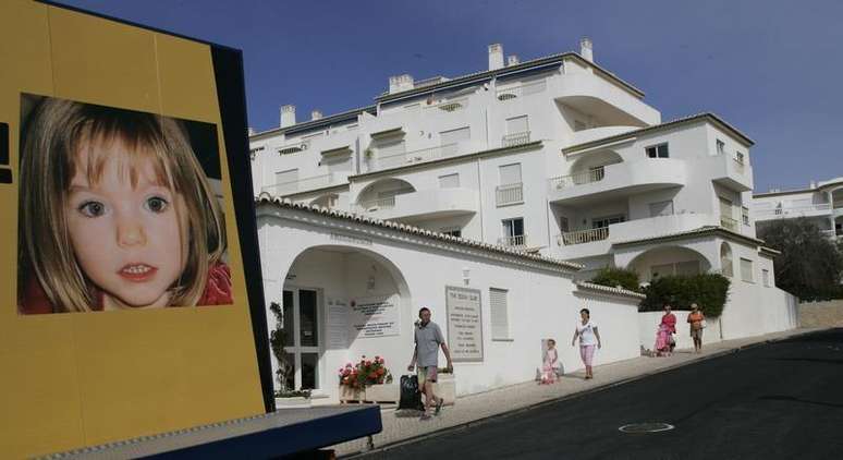 Pessoas passam perto de um painel com a foto de Madeleine no resort turístico da Praia da Luz, em Portugal.