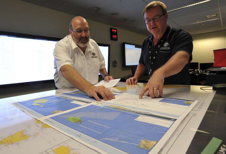 Mike Barton (esq.), que comanda a equipe de resgate australiana, mostra ao vice-premiê da Austrália um mapa da região em que as buscas estão sendo realizadas no Oceano Índico