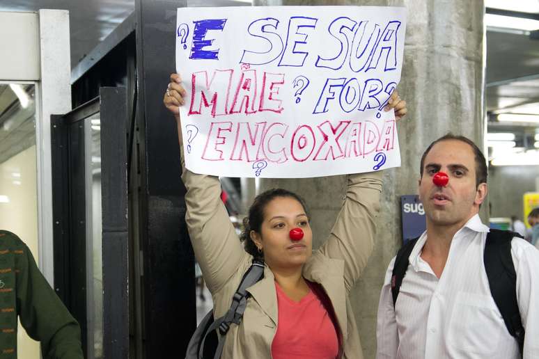 Passageira segura cartaz protestando contra abusos a mulheres nos trens do metrô de São Paulo