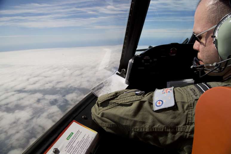 <p>Oficial olha para fora do cockpit de um avião da Força Aérea australiana, enquanto busca pelo voo MH370 da Malaysian Airlines sobre o Oceano Índico meridional, em 27 de março</p>