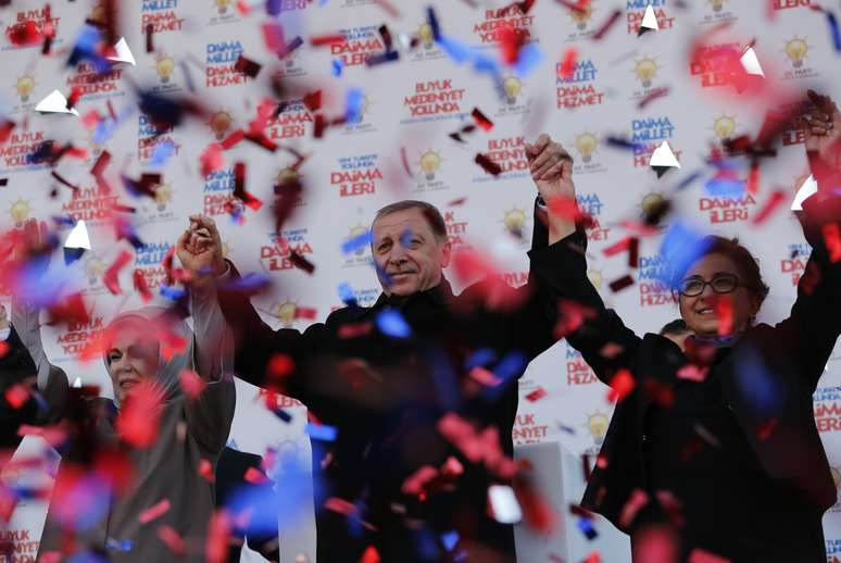 <p>Primeiro-ministro turco Tayyip Erdogan, ao centro, acompanhado de sua esposa e do candidato a prefeito Maltepe Edibe Sozen Yavuz, cumprimenta seus partidários durante um comício eleitoral do seu Partido AK, em Istambul, neste sábado, 29 de março</p>