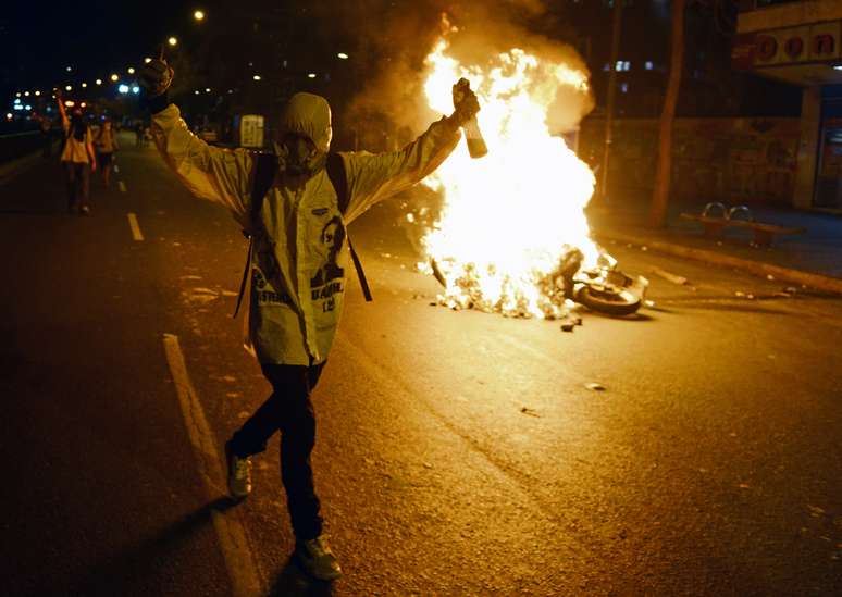 <p>Manifestantes anti-governo deixam uma barricada em chamas durante um protesto em Caracas, nesta segunda-feira, 31 de março</p>