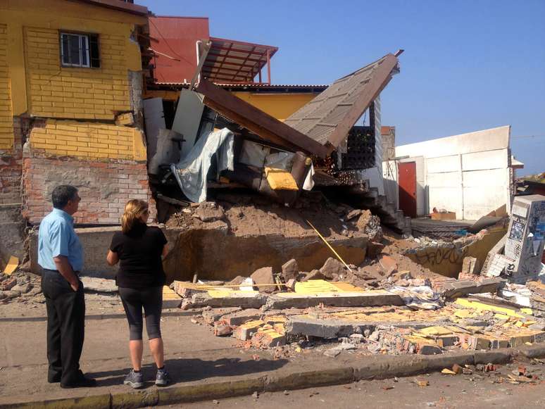 <p>Pessoas olham para uma casa danificada pelo&nbsp;forte terremoto de magnitude 8,2 que atingiu a costa do Pac&iacute;fico do Chile, em Iquique, norte do pa&iacute;s, em 2 de abril</p>