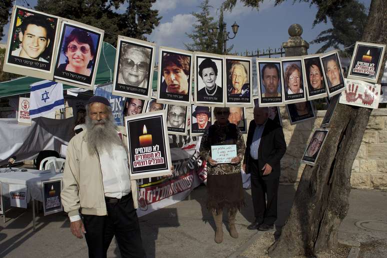 <p>Um homem israelense fica ao lado de retratos de israelenses que foram mortos por militantes palestinos, perto de uma barraca de protesto contra a liberta&ccedil;&atilde;o de prisioneiros palestinos, em frente &agrave; resid&ecirc;ncia do primeiro-ministro em Jerusal&eacute;m, em 1 de abril</p>
