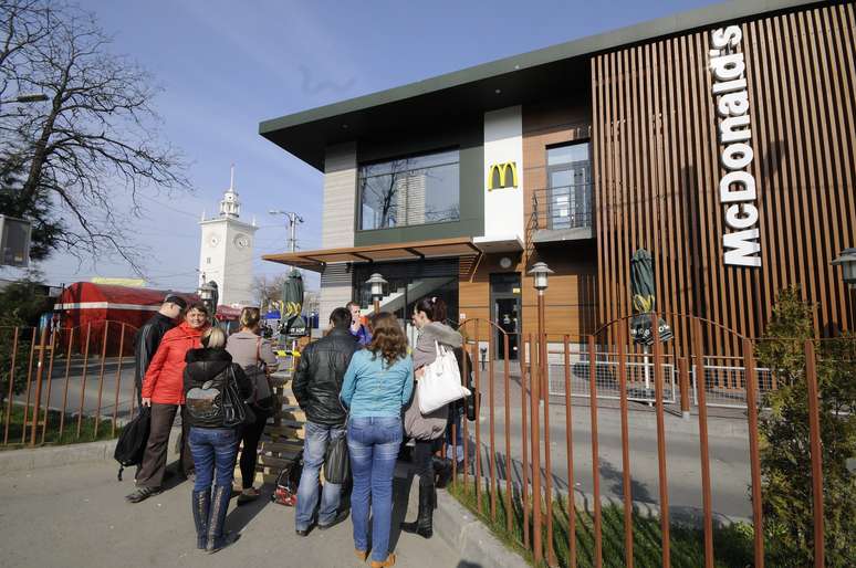 <p>Pessoas se concentram em frente ao restaurante do McDonald&rsquo;s fechado na cidade de Simferopol, na Crimeia, neste 4 de abril. A rede de fast food anunciou&nbsp;que est&aacute; fechando suas tr&ecirc;s franquias na pens&iacute;nsula</p>