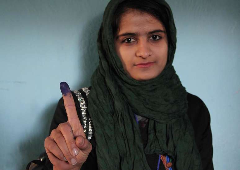 <p>Afegã mostra o dedo manchado de tinta após ter votado neste sábado. As eleições presidenciais deste 5 de abril marcam a primeira transição democrática do país</p>