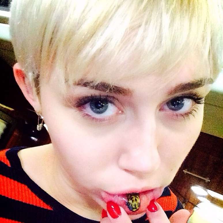 Miley Cyrus tatua no lábio gatinho com uma lágrima igual ao "emoji", desenhos usados em mensagens de celular