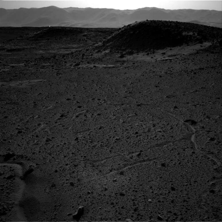 <p>Ponto luminoso aparece no fundo da foto, próximo às "montanhas", no horizonte de Marte</p>