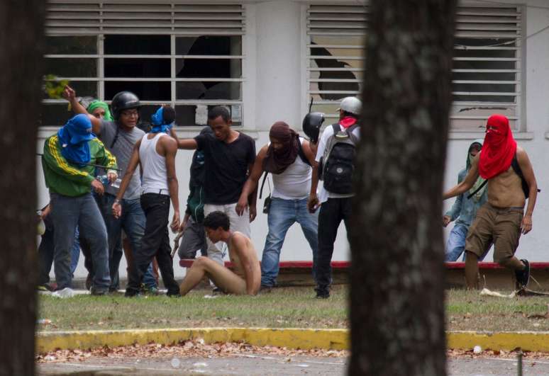 <p>Estudante é agredido e despido por partidários do governo de Nicolás Maduro, durante manifestação na Universidade Central da Venezuela, em Caracas</p>