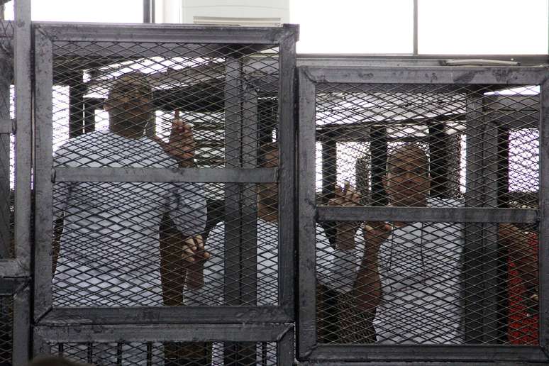 <p>O chefe do escritório da Al-Jazeera em inglês, Mohammed Fahmy, o produtor Baher Mohamed e o correspondente Peter Greste assistem ao julgamento, em 31 de março, em jaulas </p>