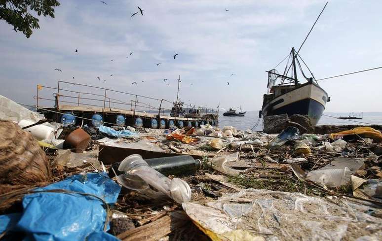 Lixo visto perto de um barco de pesca na praia do Fundão, na baía de Guanabara, no Rio de Janeiro. O governo do Estado do Rio de Janeiro assumiu nesta quinta-feira que vai ser necessário "enxugar gelo" para garantir as condições de limpeza da baía de Guanabara para a realização das provas de vela dos Jogos Olímpicos de 2016. 13/03/2014