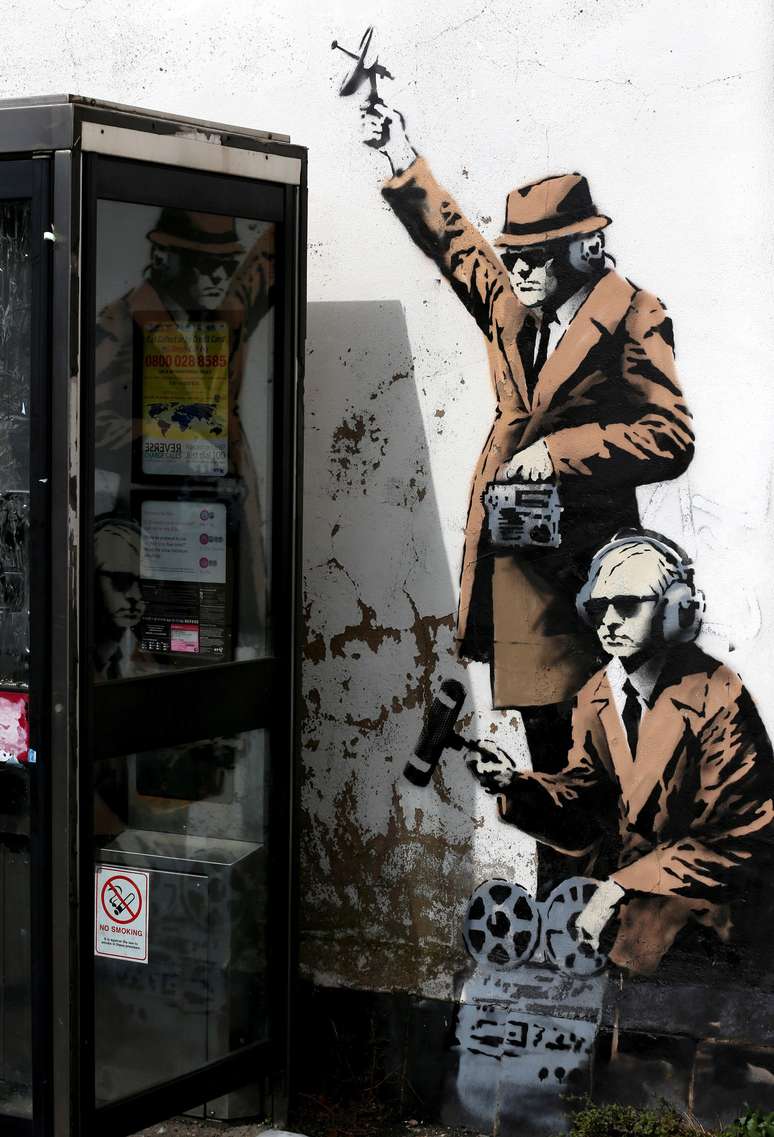 Um estêncil que seria do artista Banksy se tornou atração turística em Cheltenham, na Inglaterra. Na obra, homens que aparentam serem detetives "investigam" a cabine telefônica.