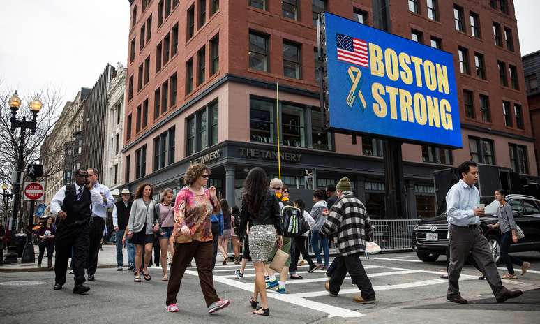 <p><strong>14 de abril -</strong> pedestres caminham em frente a uma painel eletrônico onde se lê o lema: "Boston forte", próximo à linha de chegada da maratona de 2014. Três pessoas morreram e 264 ficaram feridas na explosão de duas bombas em 15 de abril de 2013 </p>