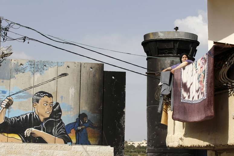 <p>Uma mulher lava roupa dentro de campo de palestinos refugiados em Aida, Cisjordânia</p>