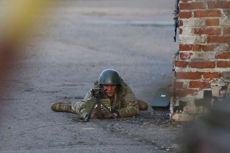 <p>Um soldado ucraniano aponta sua arma contra os manifestantes pró-Rússia que se reuniram em frente de uma base aérea ucraniana em Kramatorsk, no leste da Ucrânia. Pró-russos que ocupavam um aeroporto da cidade foram alvo de uma operação de tropas ucranianas nesta terça-feira</p>