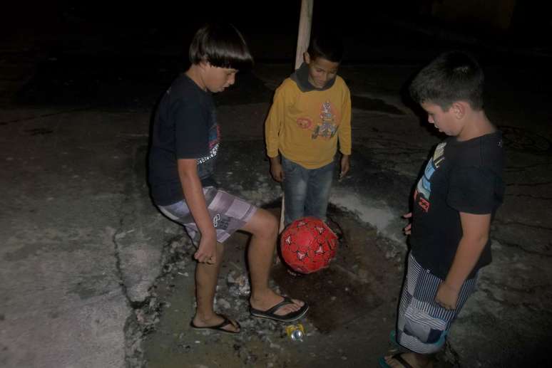 Crianças brincam de bola em cratera na zona sul de São Paulo