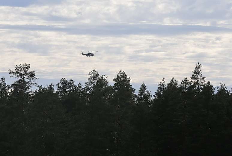 <p>Helicóptero sobrevoa área próxima a Jamijarvi Airfield, sudoeste da Finlândia, onde um pequeno avião que transportava paraquedistas caiu neste domingo </p>