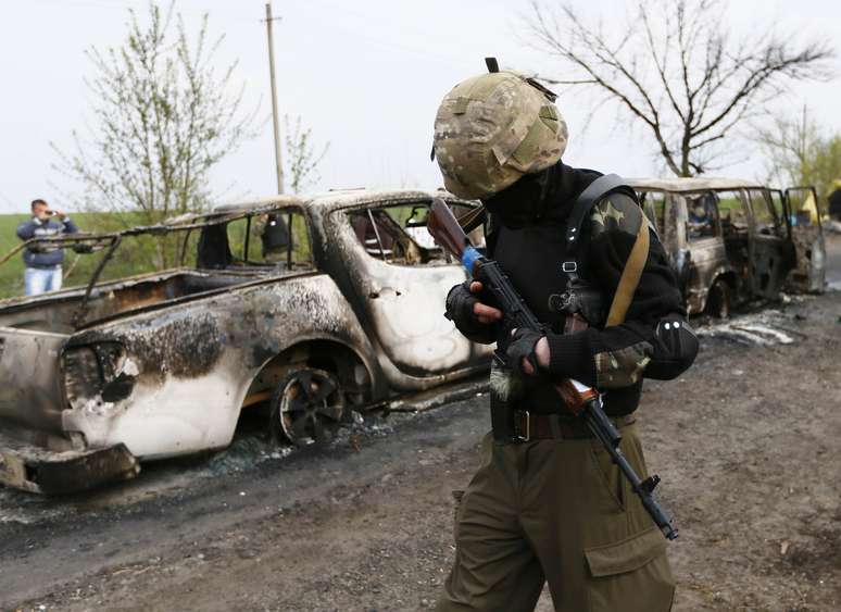 <p>Soldado passa ao lado de carro incendiado após ataque neste domingo, que gera tensão dias depois de umacordo feito na Genebra para aliviar crise no país</p>
