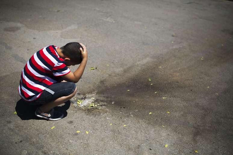 Menino olha uma mancha feita pelo foguete lançado em Israel nesta segunda-feira