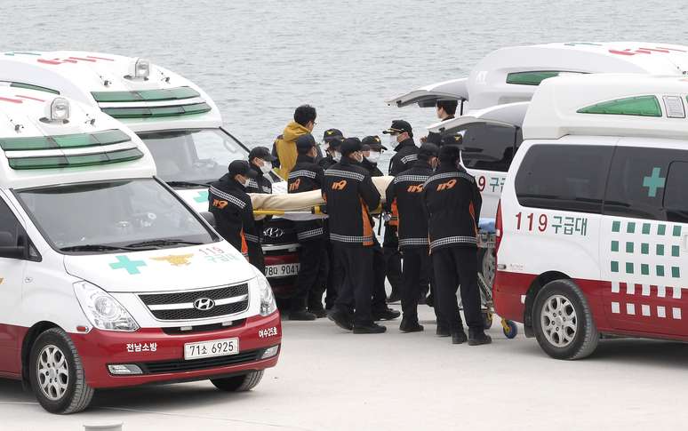 Corpo de mais uma vítima é levado para ambulância; número de mortos já passou de 100
