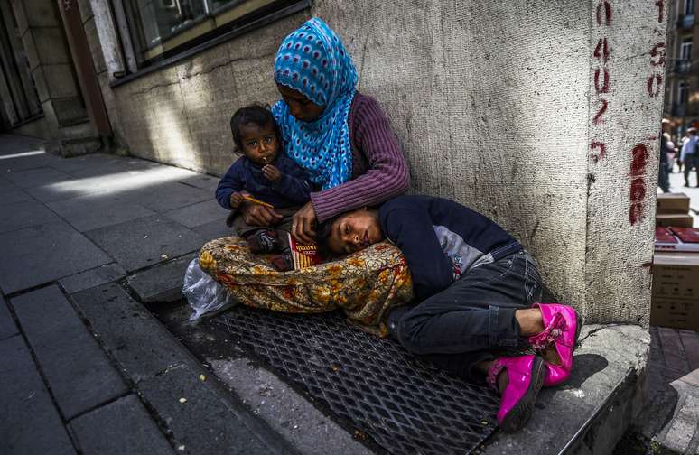 <p>Mulher s&iacute;ria &nbsp;&eacute; vistacom os filhos na cal&ccedil;ada, no centro de Istambul, nesta ter&ccedil;a-feira,&nbsp;22 de abril</p>