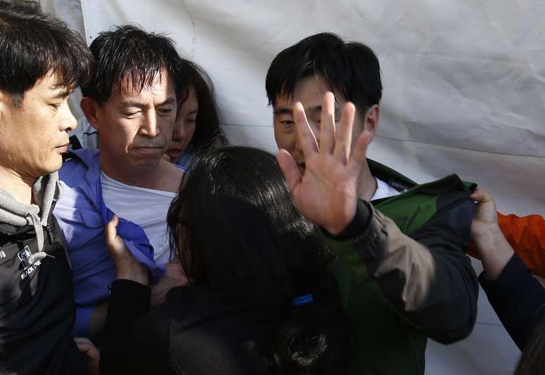 <p>Familiares&nbsp;de passageiros&nbsp;a bordo da balsa que naufragou na costa sul-coreana agrediram&nbsp;Choi Sang-hwan, vice-chefe da guarda costeira do pa&iacute;s (zom camisa azul)&nbsp;e um funcion&aacute;rio do governo (a direita),&nbsp;em Jindo, nesta quinta-feira, 24 de abril</p>