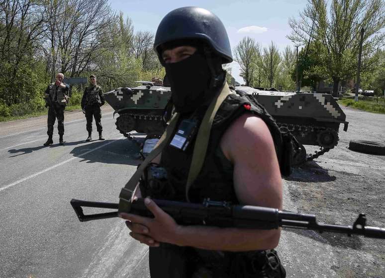 <p>Soldados ucranianos montam guarda perto de um ve&iacute;culo blindado em um posto de controle fora da cidade de Slaviansk, em 27 de abril</p>