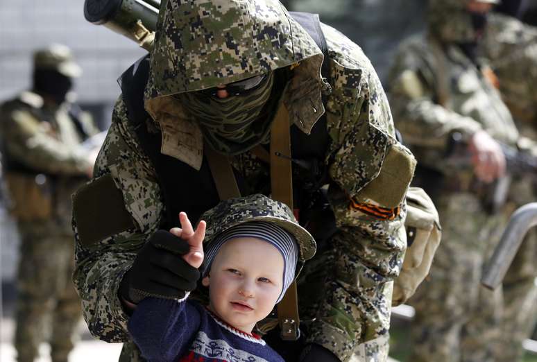 <p>O menino posa para uma foto com um homem armado pró-Rússia em frente ao prédio ocupado da administração da cidade de Kostyantynivka, no leste da Ucrânia, em  28 de abril</p>