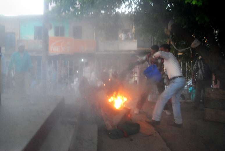 <p>Espectadores indianos tentam apagar o fogo do corpo de um homem chamado pela polícia como Durgesh Kumar Singhb, durante um debate eleitoral televisionado, em um parque local da cidade de Sultanpur, na Índia</p>