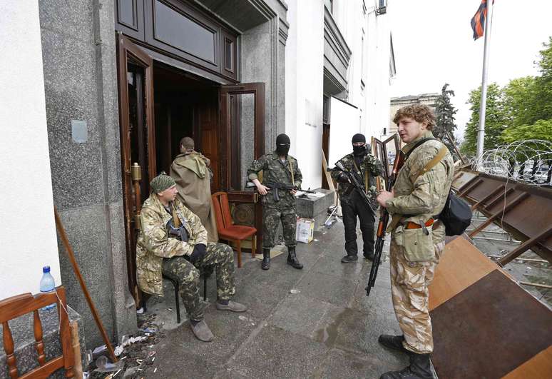 <p>Homens armados pró-Rússia se reúnem na entrada da sede do governo regional em Luhansk</p>