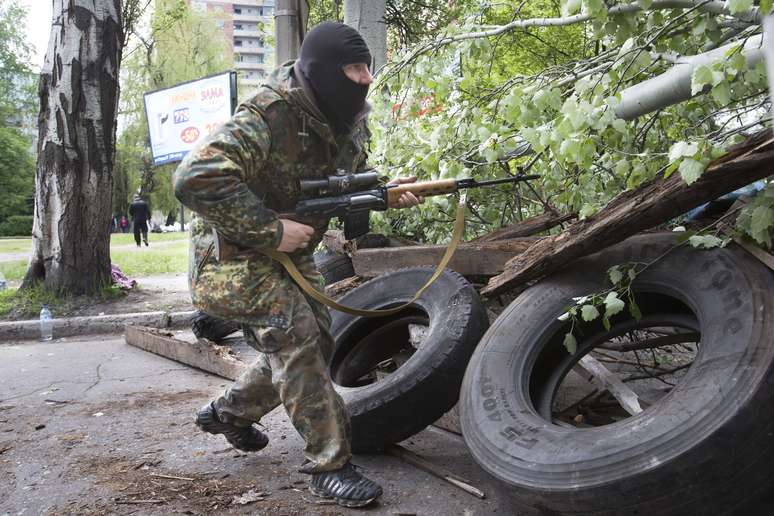 <p>Um homem armado pro-russo corre atr&aacute;s de barricadas segurando uma arma na cidade de&nbsp;Slovyansk, leste da Ucr&acirc;nia, nesta sexta-feira, 2 de maio</p>