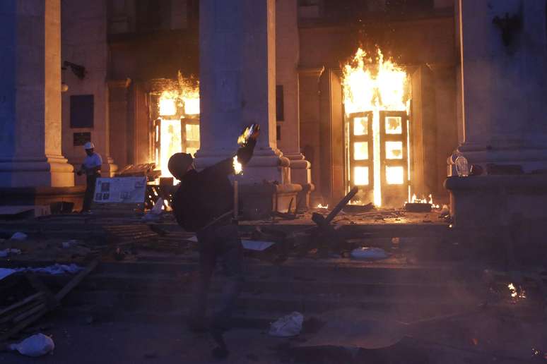 <p>Um manifestante joga um coquetel molotov em prédio em chamas, na cidade de Odessa, na Ucrânia, em 2 de maio</p>
